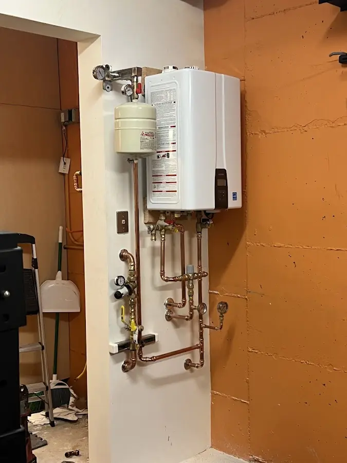 Plumbing technician inspecting water heater connections in Summerset